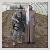 Wake County Farm Bureau Member 1st Lt. John Burt poses with the leader of a local farmers’ association in a greenhouse funded with micro-grant money.