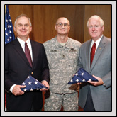 Sgt. 1st Class Ken Colvin presents flags to Steve Carroll (left), general manager of NCFB Mutual Insurance Company, and Farm Bureau President Larry Wooten (right). The flags were flown in Iraq.